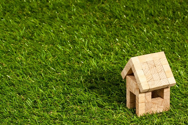 Artificial Turf Installation Costs - Close up photo of a model house made of wooden building blocks sitting on an artificial turf lawn